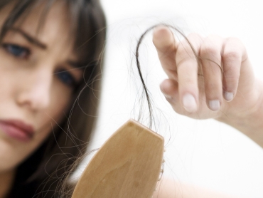 Portrait of a young woman brushing her hair, close up (studio)