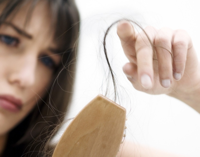 Portrait of a young woman brushing her hair, close up (studio)